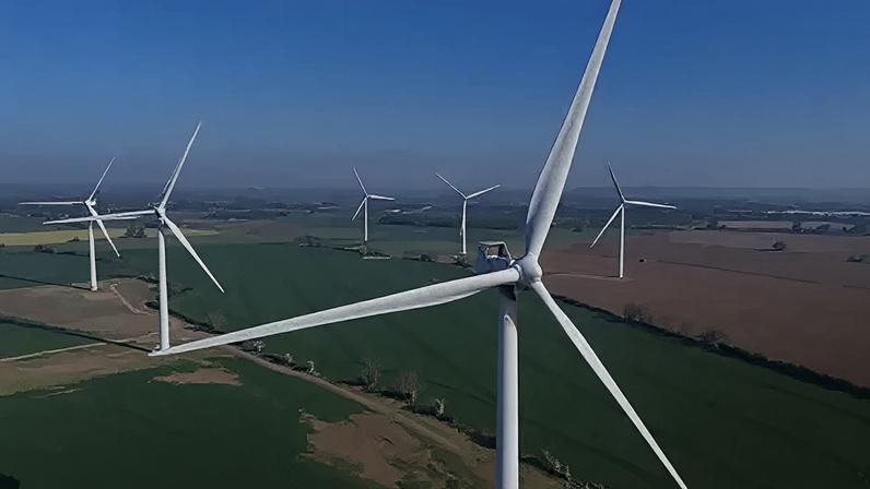 EPA An aerial view of a wind farm in countryside. In the foreground is a very large white wind turbine. The tower supports three long blades. Several more wind turbines are arranged in across the fields. Low hedgerows separate some of the fields.
