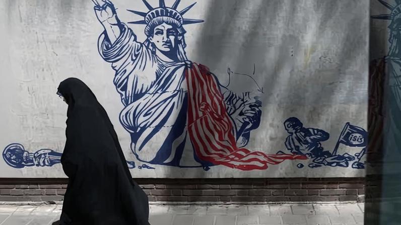A woman walks past an anti-US mural on a street in Tehran, Iran.