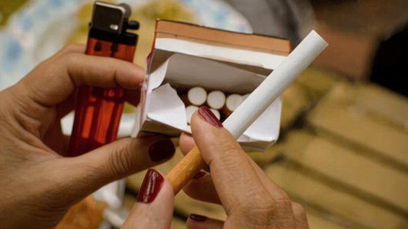 Close up of a woman's hands picking up cigarette from a box of cigarettes