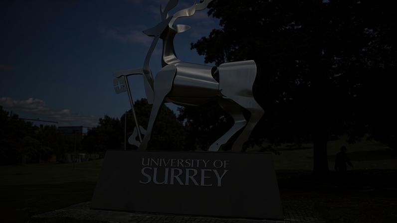 A large metal stag sculpture stands on a plinth at the University of Surrey