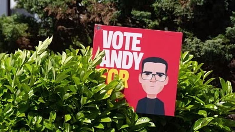 A 'vote Andy' placard among bushes and trees