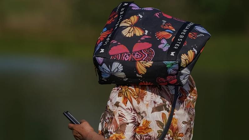 A person protects their head from the sun on Wimbledon Common in London on 25 May when temperatures for May hit record highs of 35C.