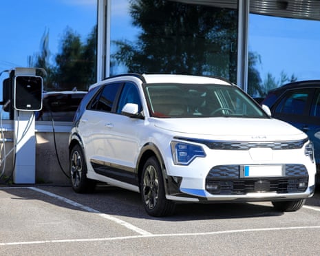 Kia Niro parked next to a battery charger at a car showroom