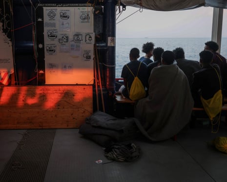 Rescued people look out from onboard a migrant search and rescue ship as it arrives in the port of Salerno, Italy, in August last year.