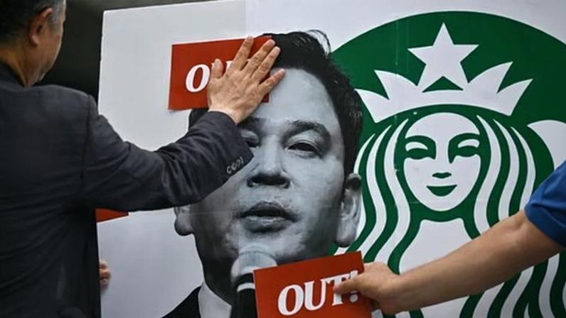 People in Seoul put stickers on an image of the Shinsegae chairman Chung Yong-jin, whose company operates Starbucks in South Korea, during a rally calling for a boycott of the coffee chain in Seoul.