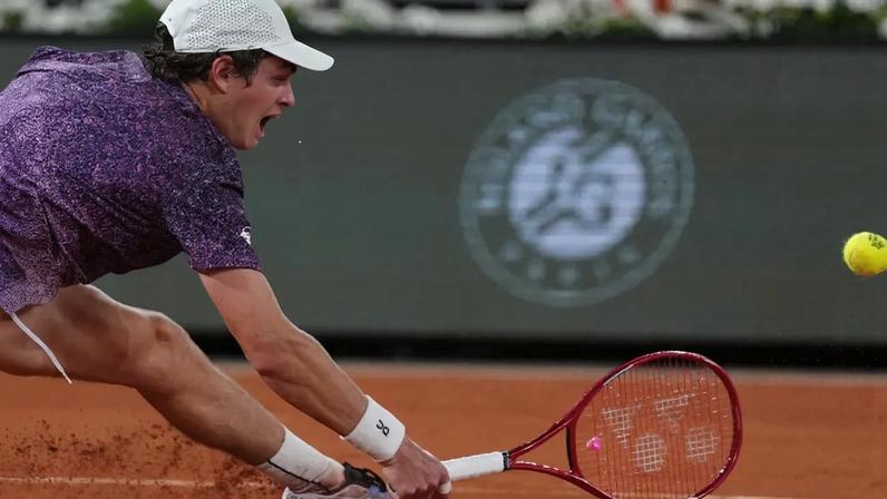 O brasileiro João Fonseca escorrega na quadra de saibro para rebater a bola contra o norueguês Casper Ruud durante a partida de simples masculina no oitavo dia do torneio de tênis de Roland Garros, na quadra Philippe-Chatrier, em Paris (Foto: Dimitar Dilkoff / Afp)