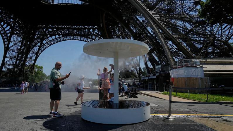 People cool off in a water spray at the Eiffel Tower in Paris, Sunday, June 21, 2026. Image by Michel Euler, Associated Press.