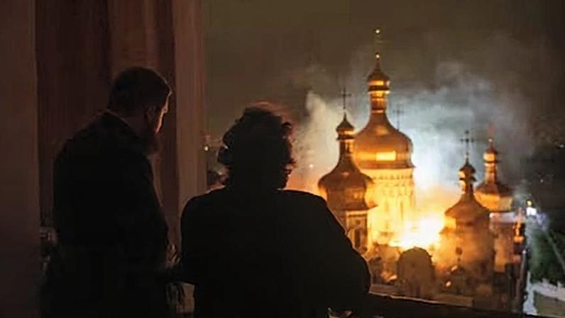 El obispo Avraamiy, de pie a la derecha, observa la Catedral de la Dormición en llamas tras el bombardeo ruso