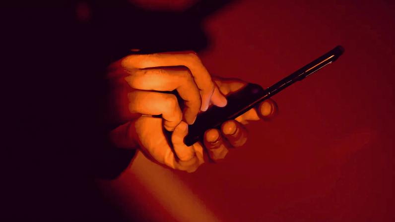 Person using smartphone in dark room with red light