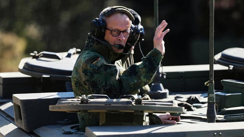 German Chancellor Friedrich Merz waves as he is driven in a GTK Boxer tank at the German army barracks in Munster, northern Germany, on April 30, 2026, as they visit the troops of the German Army.