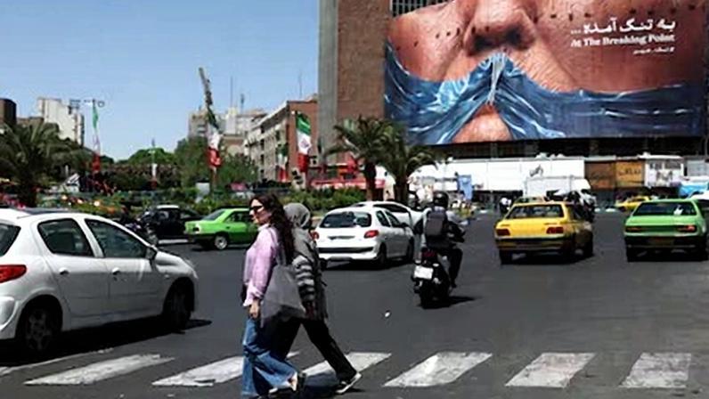 Dos mujeres cruzaban este sábado una calle de Teherán junto a un mural sobre el estrecho de Ormuz.