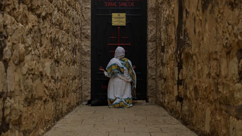 A woman kneels in front of the entrance to Gethsemane grotto in Jerusalem on May 21.