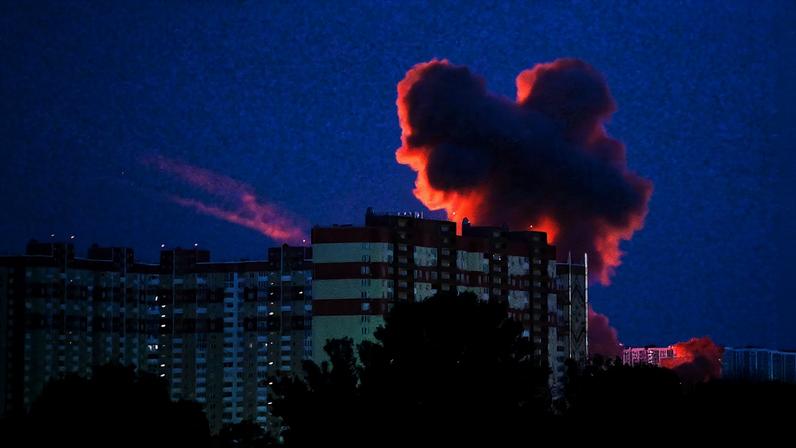 Smoke billows above high-rise buildings after Russian missile and drone strikes target Kyiv. It is nighttime.