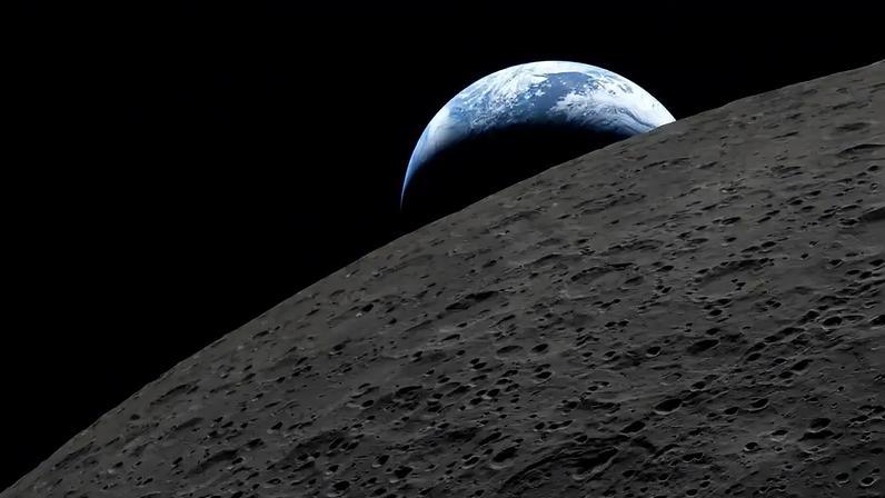 A Terra azul e branca surge no horizonte lunar, que mostra sua superfície cinza escura e crateras em primeiro plano, contra o espaço preto.