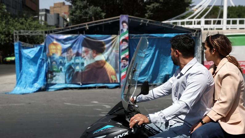 Una pareja pasa este miércoles en moto frente a un cartel en Teherán con la imagen del fallecido líder supremo iraní, Ali Jameneí.