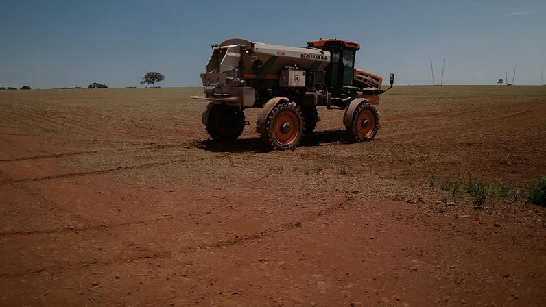 Trabalhador rural dirige trator espalhando fertilizante em campo de soja, perto de Brasília (DF)