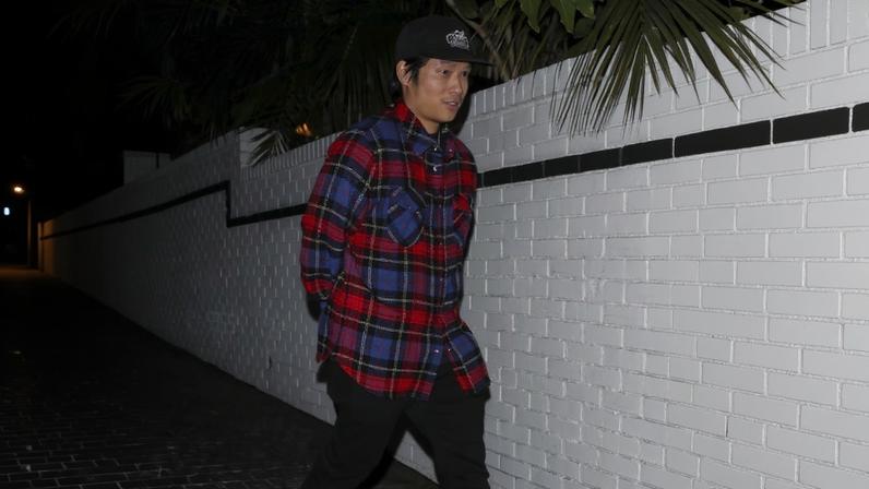 Pax Jolie-Pitt exiting the Chateau Marmont in a red plaid shirt, black pants, and red sneakers.