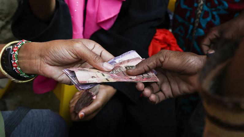 People handing each other Kenyan currency bills.