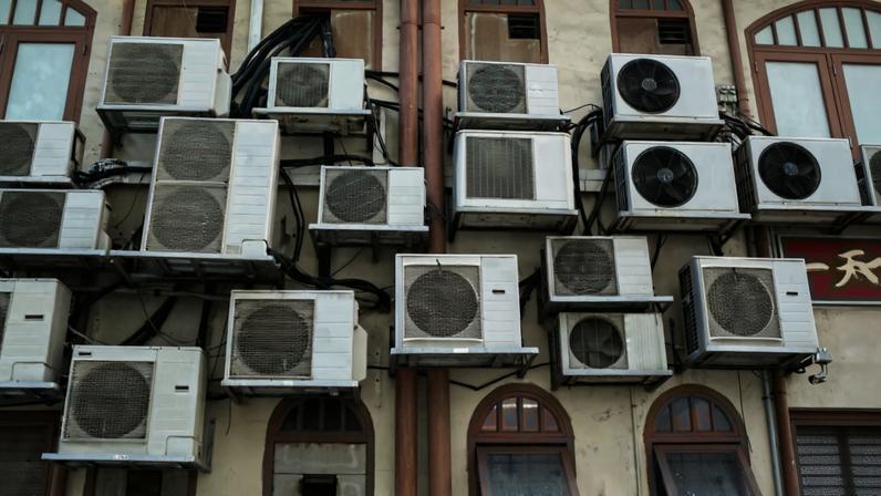 The outside of a building with numerous air conditioner compression units.
