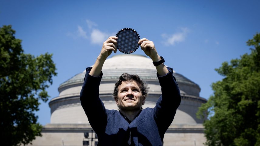 Jarillo-Herrero stands in front of the MIT dome, holding a circular wafer displaying moire patterns over his head