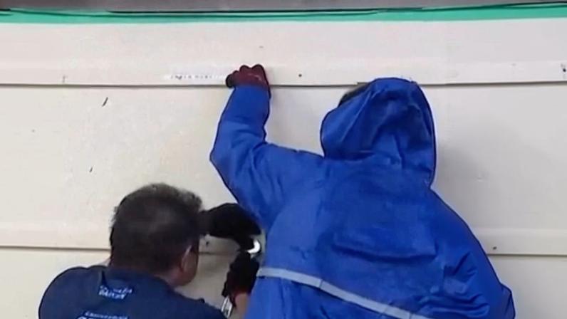 Two men board up a building