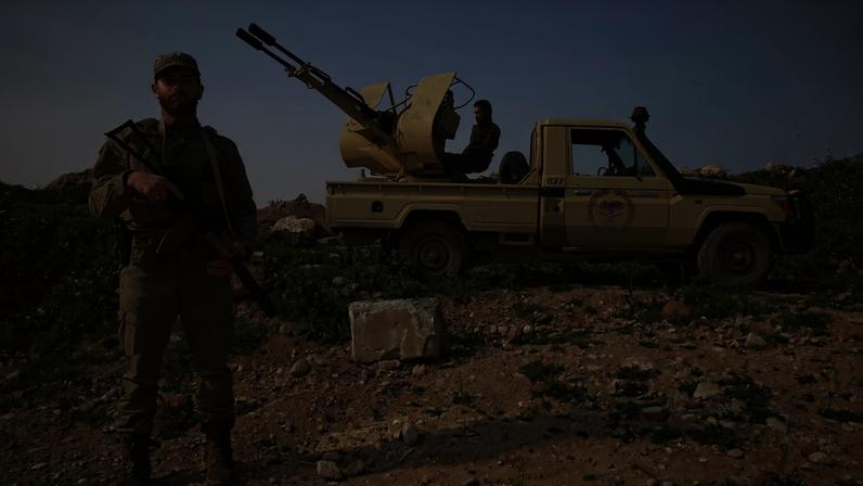 A Syrian army soldier stands guard next to an armored vehicle positioned along the Syria-Lebanon border in the rural area of Qusayr on April 1.