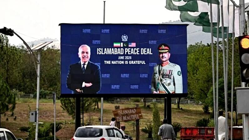 A billboard shows Pakistani Prime Minister Shehbaz Sharif and Pakistani Army Chief Asim Munir. Between them, the words "Islamabad Peace Deal June 2026 The Nation Is Grateful" are written below crossed U.S. and Iranian flags.