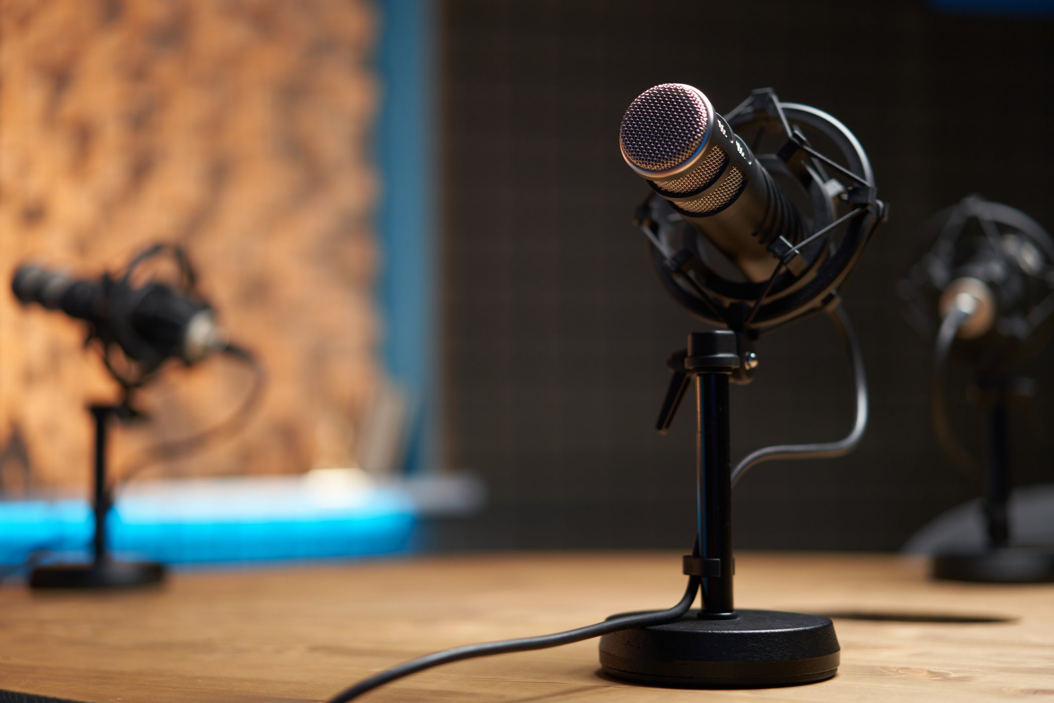 Milionários revelam 4 hábitos que formam líderes de sucesso extraordinários Microfone moderno em foco suave colocado sobre uma mesa de madeira em estúdio de gravação durante um podcast (Foto: Sergey Mironov/Getty Images)
