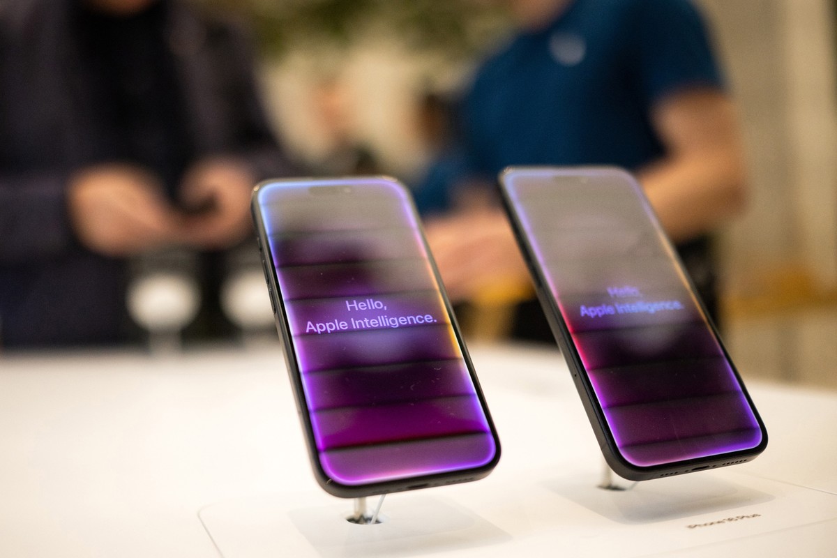 Apple enfrenta críticas e pressões por inovações em inteligência artificial amid queda de ações Telas de boas-vindas de Inteligência Artificial em smartphones iPhone 16 em uma loja da Apple (Foto: Chris Ratcliffe/Bloomberg)