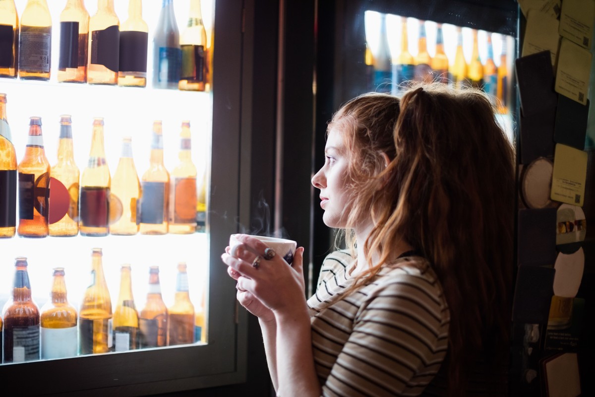 Deixar de beber álcool provoca mudanças significativas a partir do primeiro dia Mulher observa a prateleira de álcool (Foto: Freepik)
